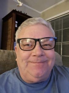 Donald J. Claxton, July 2025 Donald J. Claxton smiling while seated indoors, wearing glasses and a blue shirt.